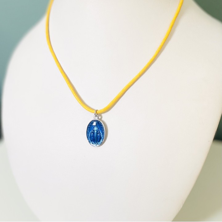 Jolie médaille miraculeuse en résine bleue sur un cordon coton à nouer.