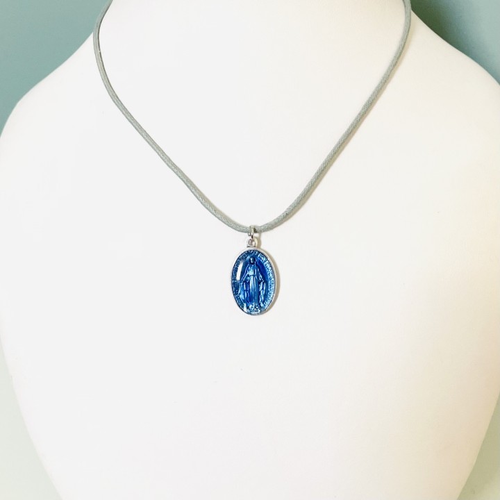 Jolie médaille miraculeuse en résine bleue sur un cordon coton à nouer.