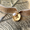Bracelet médaille croix sur ruban élastique doré.