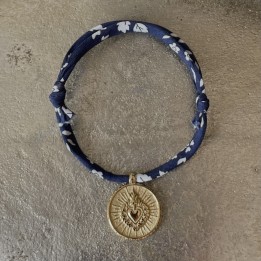 bracelet en coton Liberty coulissant mettant en valeur une médaille ex voto du Cœur Sacré en acier doré inoxydable.